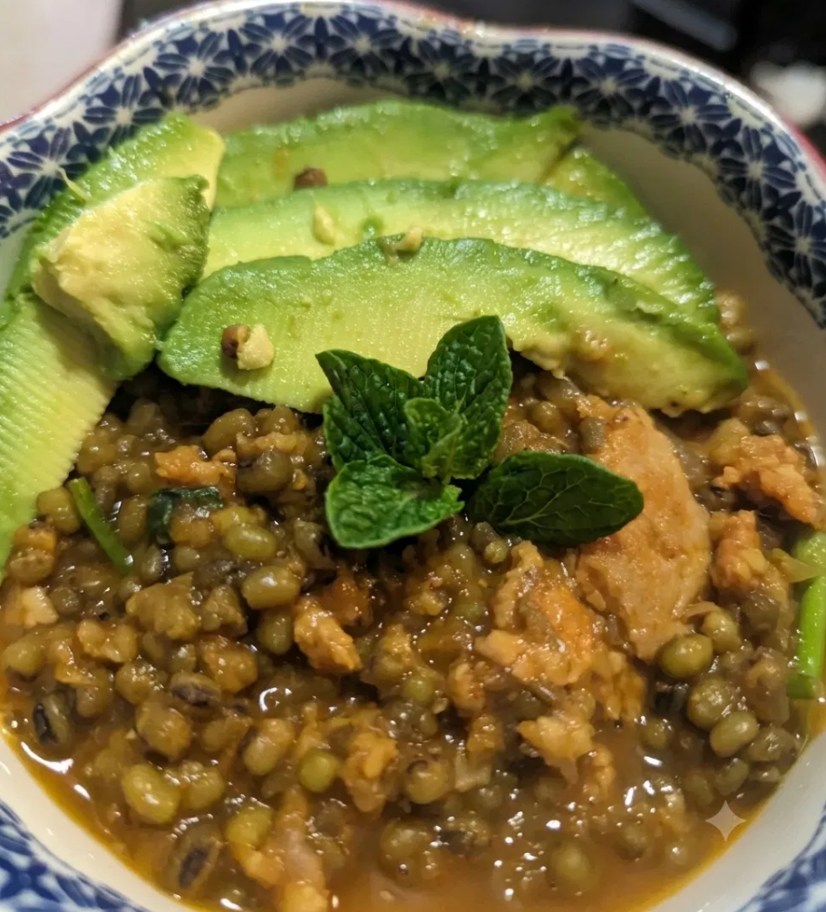 A bowl of Green Grams (Ndengu) stew topped with fanned avocado slices and fresh mint